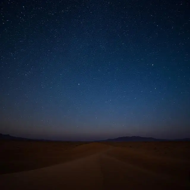 Starry night sky over a desert landscape